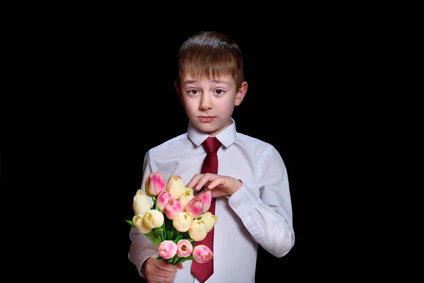 Милий хлопчик у білій сорочці з букетом тюльпанів. Ізольовані на чорному тлі — стокове фото