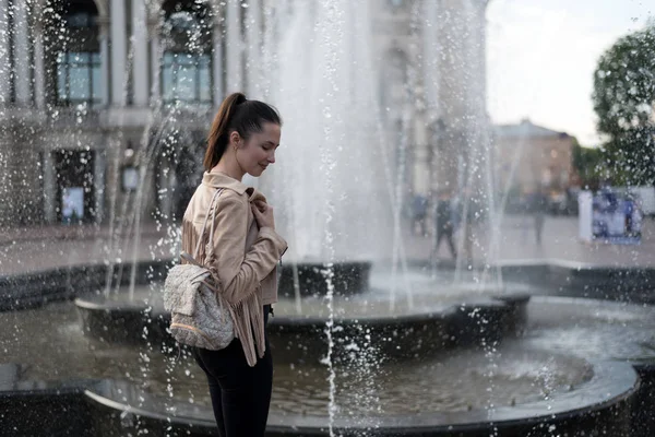 Chica de pie cerca de la fuente. Fin de semana en Europa. Un chorro de agua . —  Fotos de Stock