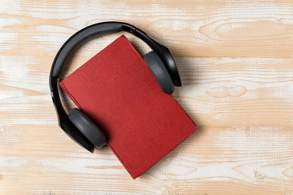 Hörlurar och en bok. Lyssna på boken. Ljudbokskoncept. Ovanifrån, kopiera utrymme. — Stockfoto