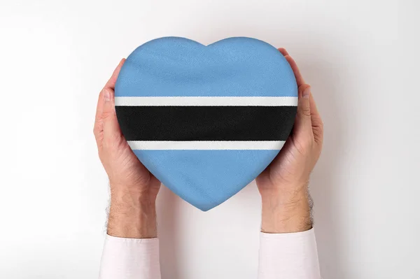 Bandera de Botswana en una caja en forma de corazón en manos masculinas. Fondo blanco —  Fotos de Stock