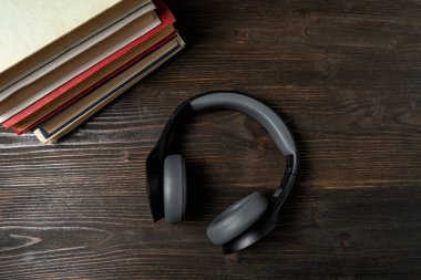 Kulaklık ve kitap. Ses öğrenme konsepti. Koyu ahşap arka plan. Üst görünüm