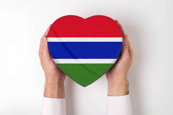 Flagga av Gambia på en hjärtformad låda i en manlig händer. Vit bakgrund — Stockfoto