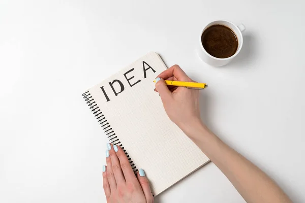 Women holding a pen writing in notebook idea. Notepad with ideas, cup of coffee on a white background. — 스톡 사진