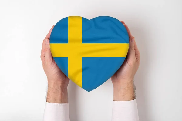 Bandiera della Svezia su una scatola a forma di cuore in mani maschili. Fondo bianco — Foto Stock