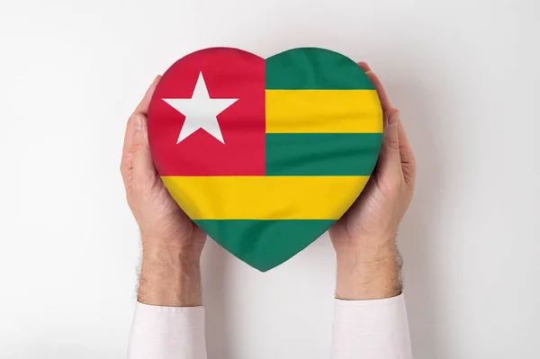 Σημαία του Τόγκο σε κουτί σε σχήμα καρδιάς σε αντρικά χέρια. Λευκό φόντο — Φωτογραφία Αρχείου