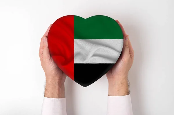 Zászló az Egyesült Arab Emírségek egy szív alakú doboz egy férfi kezében. Fehér háttér — Stock Fotó