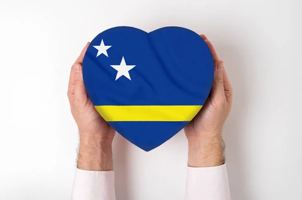 Curacao zászlója egy szív alakú dobozon, férfi kezekben. Fehér háttér — Stock Fotó