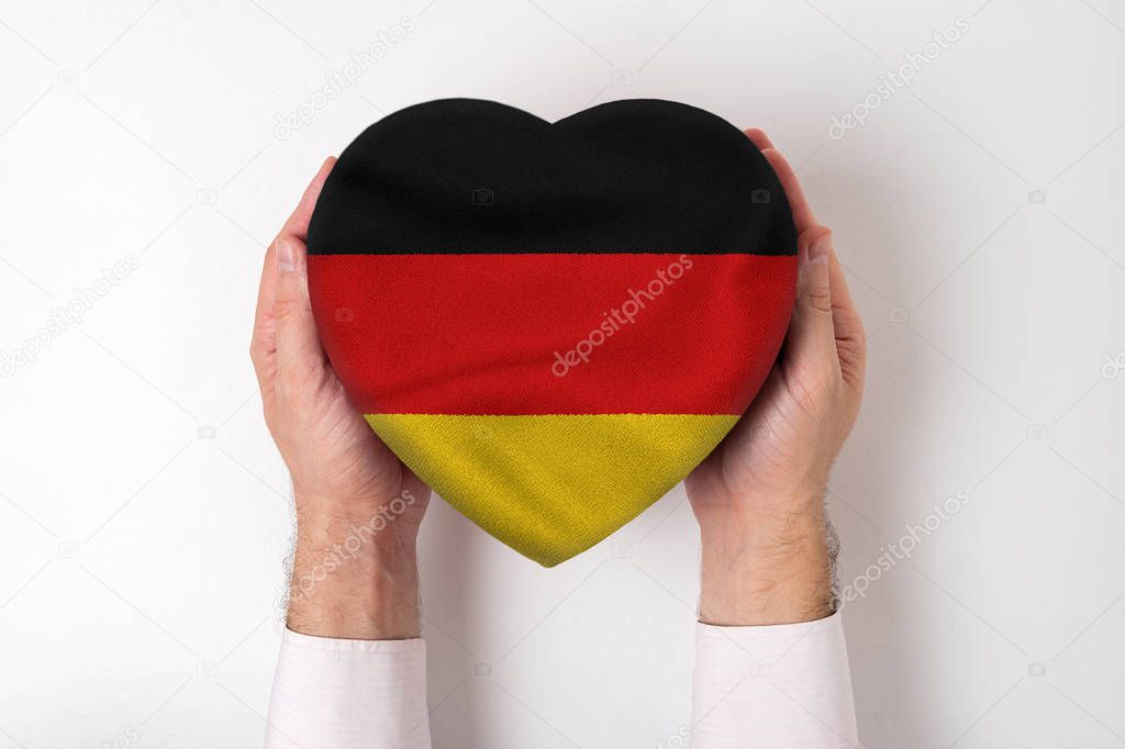 Flag of Germany on a heart shaped box in a male hands. White background