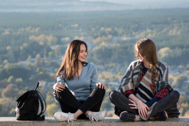 İki kız arkadaş doğanın arka planında oturuyor. En iyi arkadaşınla seyahat et. Ön görünüm.