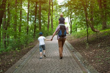 İki çocuklu baba parkta yürüyor. Ailenle seyahat etmek. Bekar bir baba. Arka plan