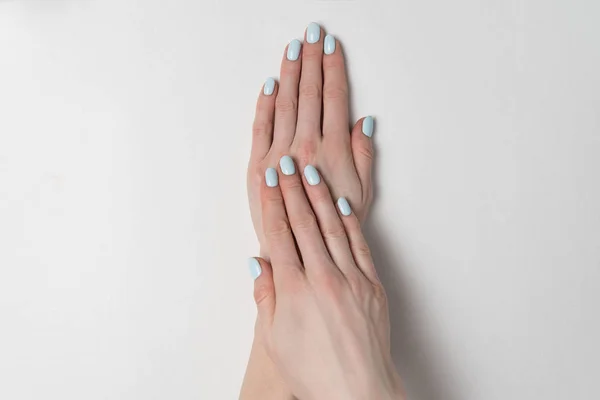 Blå manikyr på korta naglar. Händerna på vit bakgrund. Salong — Stockfoto