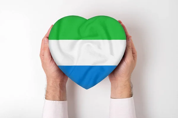 Bandera de Sierra Leona en una caja en forma de corazón en manos masculinas. Fondo blanco — Foto de Stock