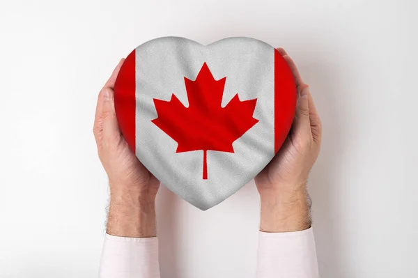 Bandera de Canadá en una caja en forma de corazón en manos masculinas. Fondo blanco — Foto de Stock