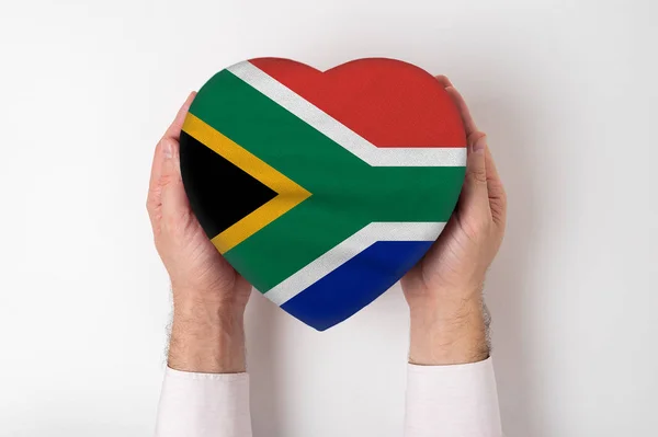 Bandeira da África do Sul em uma caixa em forma de coração em mãos masculinas. Fundo branco — Fotografia de Stock