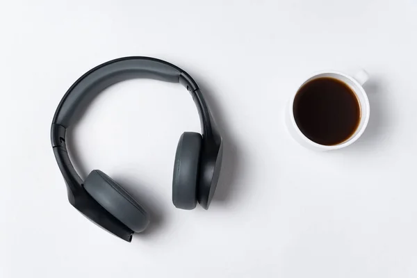 Fones de ouvido e xícara de café no fundo branco, vista superior. Minimalismo . — Fotografia de Stock