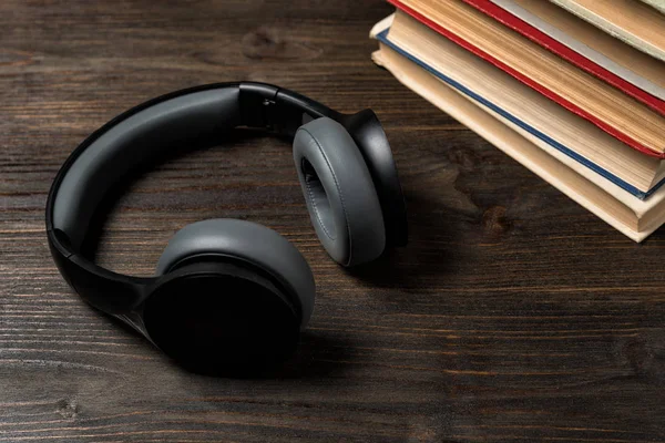 Auriculares con libros sobre fondo de madera. Leer y escuchar música . —  Fotos de Stock