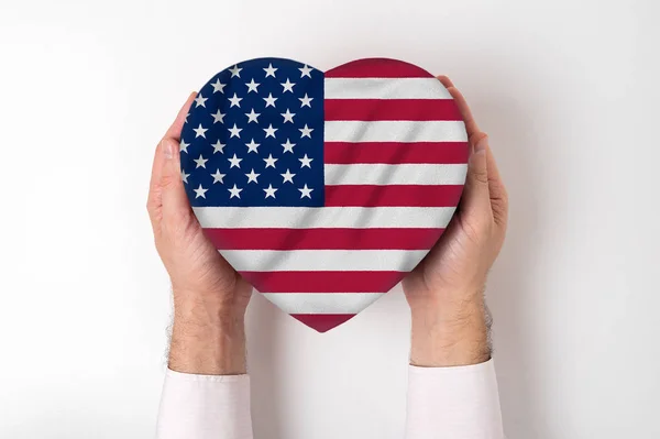 Drapeau des États-Unis sur une boîte en forme de coeur dans une main masculine. Fond blanc — Photo