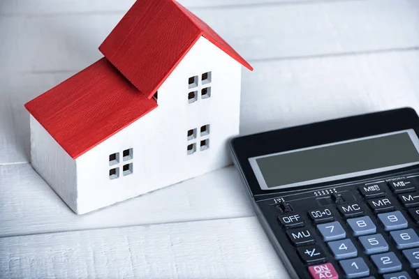 Home model and calculator on white background. Buying house concept. Closeup