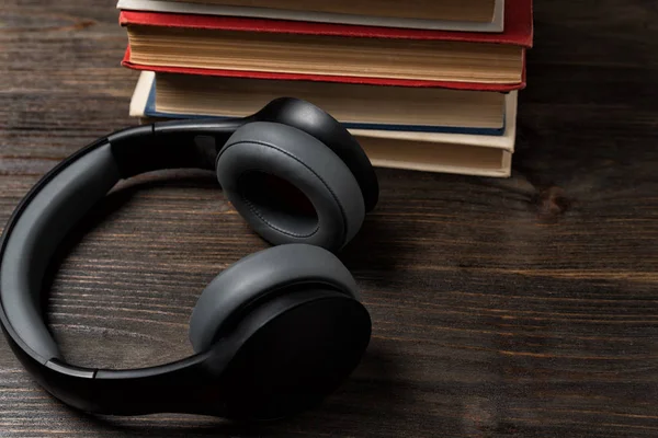 Libros y auriculares estéreo. Escucha música y lee. Fondo de madera, primer plano —  Fotos de Stock