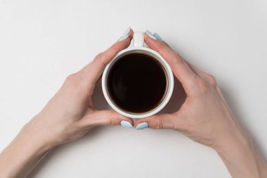 Beyaz arka planda bir fincan kahveyi tutan kadın eli. Bir kupa çay, kadınların elinde..