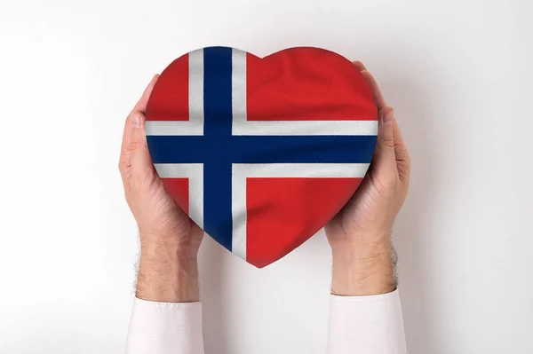 Norges flagga på en hjärtformad låda i en manlig hand. Vit bakgrund — Stockfoto