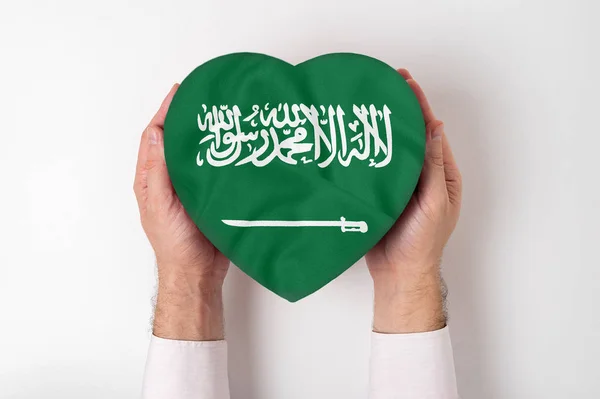 Saudiarabiens flagga på en hjärtformad låda i en manlig hand. Vit bakgrund — Stockfoto