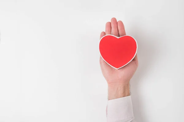 Pequeña caja roja en forma de corazón en la palma masculina sobre un fondo blanco. Copiar espacio — Foto de Stock