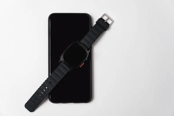 Relojes inteligentes están en el teléfono móvil. Fondo blanco, aislado. Concepto de tecnología moderna . — Foto de Stock