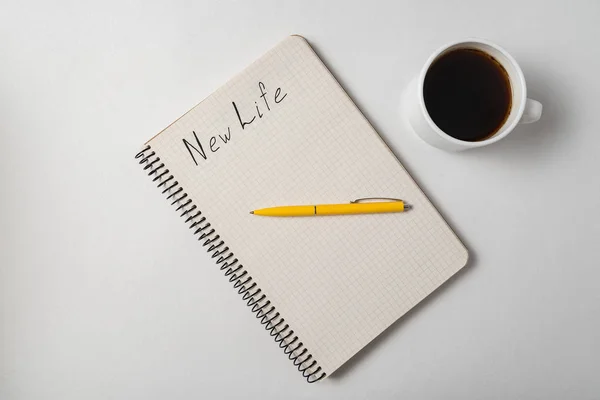 Top view of notebook with New Life inscription. Copybook, pen and cup of coffee on white background — 스톡 사진