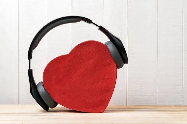 Wireless full-size headphones wearing a red heart-shaped box. Love music concept. Front view — Stock Photo, Image