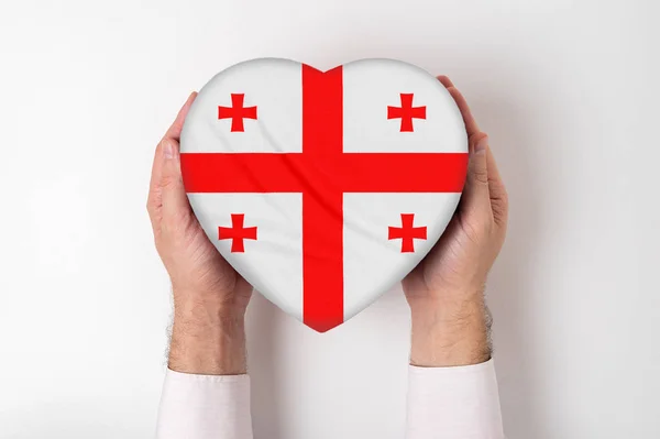 Σημαία της Γεωργίας σε κουτί σε σχήμα καρδιάς σε αντρικά χέρια. Λευκό φόντο — Φωτογραφία Αρχείου