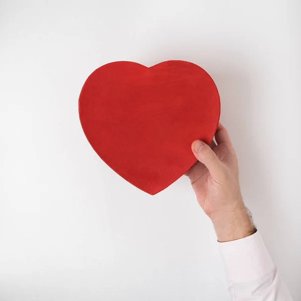 Caja en forma de corazón rojo de estilo vintage en mano masculina aislada sobre fondo blanco — Foto de Stock