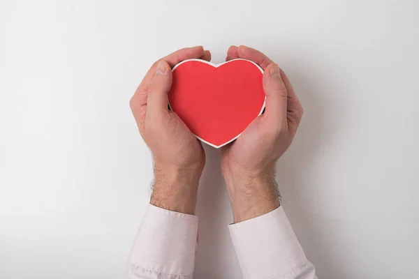 Kleine rode hartvormige doos in mannelijke hand geïsoleerd op witte achtergrond — Stockfoto