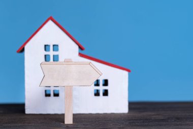 Ahşap tabelalı ev modeli. Ev konsepti satın almak. Mavi arkaplan, ön görünüm