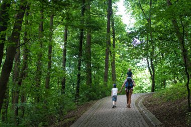 Babam oğullarıyla parkta yürüyor. Çocuk babasının omuzlarındaydı. Arka plan
