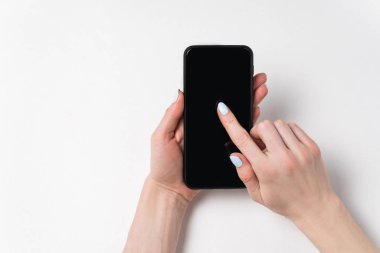 Kadın eli telefonu tutuyor ve ekranda görünüyor. Siyah ekran, beyaz arkaplan, kopyalama alanı