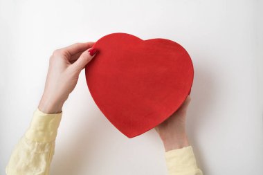 Beyaz arka planda izole edilmiş kadın ellerinde klasik kırmızı kalp şeklinde bir kutu.