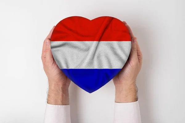 Niederländische Flagge auf einer herzförmigen Schachtel in männlicher Hand. weißer Hintergrund — Stockfoto