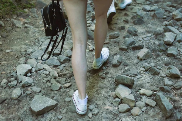 Woman legs goes on a rocky road. Hiking into the mountains. Closeup — Stock Photo, Image