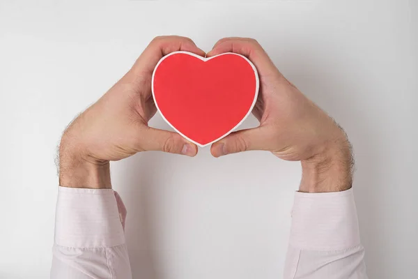 Kleine rode hartvormige doos in mannelijke hand op witte achtergrond — Stockfoto