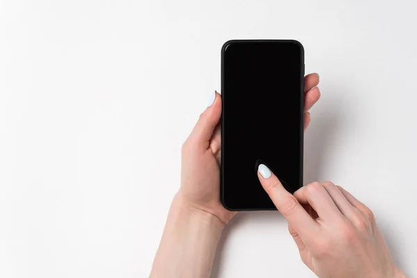 Teléfono de mano femenina con pantalla vacía. Dedo en exhibición. Copiar espacio — Foto de Stock