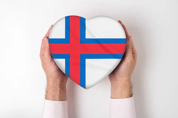 Bandiera delle Isole Faroe su una scatola a forma di cuore in mani maschili. Fondo bianco — Foto Stock