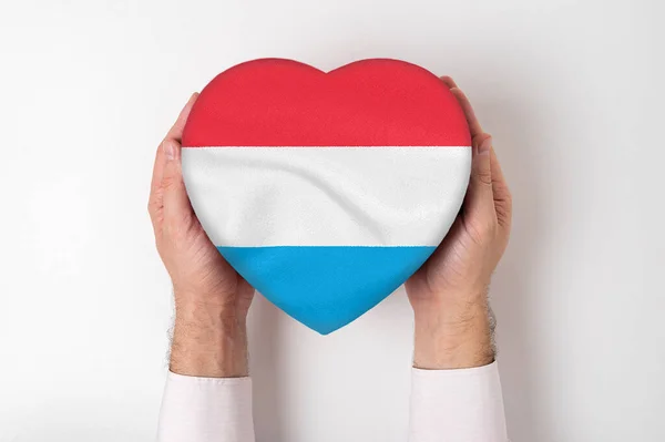 Bandera de Luxemburgo en una caja en forma de corazón en manos masculinas. Fondo blanco —  Fotos de Stock