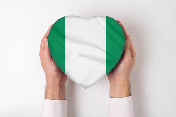 Флаг Нигерии на коробке в форме сердца в мужских руках. Белый фон — стоковое фото
