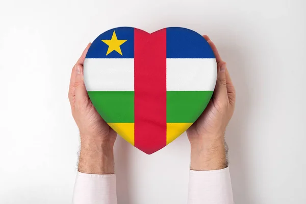 Bandeira da República Centro-Africana em uma caixa em forma de coração em mãos masculinas. Fundo branco — Fotografia de Stock