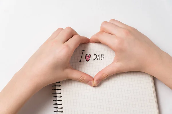 Manos de niño haciendo forma de corazón con me encanta papá aviso. Cuaderno con manuscrito. Día del Padre — Foto de Stock