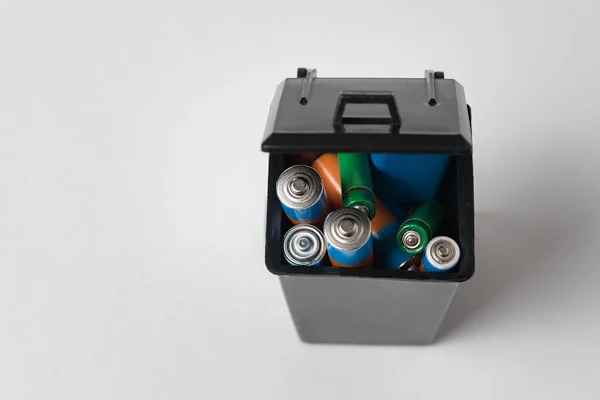 Alkaline batterijen in zwarte vuilnisbak op witte achtergrond. Recycling van batterijen — Stockfoto