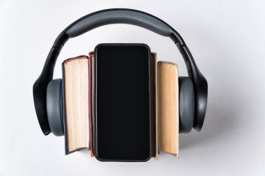 Stereo kulaklıklar, kitaplar ve beyaz arka planda bir telefon. Ses kitapları kavramı. Boşluğu kopyala