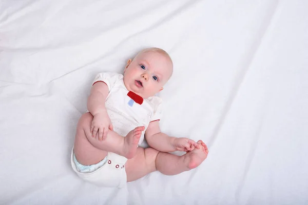 Sorprendido bebé tendido sobre una manta blanca. Recién nacido en pañales. Comodidad del niño —  Fotos de Stock