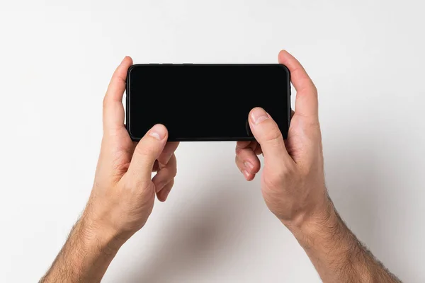 Férfi kezek kezében okostelefon fehér háttérrel. Üres képernyő. Fénymásolási hely — Stock Fotó